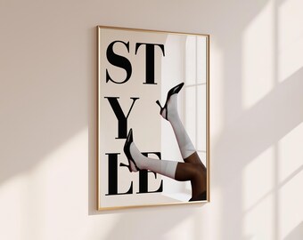 Peut inclure: Une affiche murale rectangulaire dans un cadre doré fin présentant le mot STYLE en grandes lettres capitales noires. L'image montre deux jambes portant des chaussettes blanches et des escarpins noirs à bride arrière.
