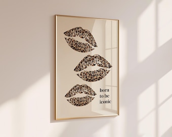 Peut inclure: Une affiche encadrée représentant trois paires de lèvres avec un motif léopard marron et noir sur fond beige. Le texte "born to be iconic" est imprimé en noir, en minuscules et en police sans empattement à droite des lèvres inférieures.