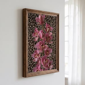 May include: A framed wall art piece featuring a vertical arrangement of pink orchid flowers set against a brown and black leopard print background. The artwork is enclosed in a medium-toned wooden frame with a simple, clean-lined profile.