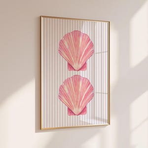 Può includere: Una stampa artistica da parete rettangolare in una sottile cornice dorata che raffigura due conchiglie di capasanta rosa impilate verticalmente. Lo sfondo della stampa è costituito da un motivo a righe verticali beige chiaro e bianco, pulito e ordinato.