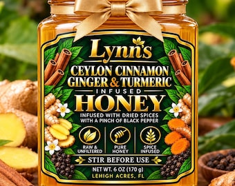 May include: A glass jar of Lynn's Ceylon Cinnamon, Ginger & Turmeric infused honey with a white lid and gold ribbon. The label features text, spice illustrations, and states Net Wt. 6 oz (170 g). The honey is amber-coloured and clear.