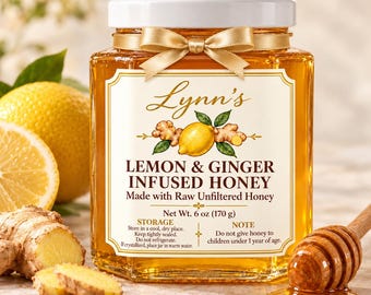 Op de afbeelding: Een zeshoekige glazen pot met Lynn's citroen- en gemberhoning, voorzien van een witte deksel en gouden lint. Het etiket vermeldt: Lynn's Lemon & Ginger Infused Honey, Made with Raw Unfiltered Honey, Net Wt. 6 oz (170 g). Inclusief bewaar- en veiligheidsinstructies.