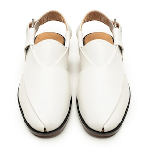 Op de afbeelding: Een paar witte leren sandalen met een puntig teenontwerp. De sandalen hebben een enkelband en een gespsluiting. De zolen zijn zwart met een bruine rand.