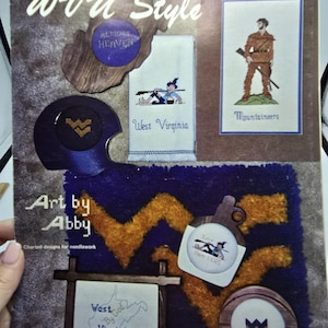 May include: A WVU Style Art by Abby needlework pattern booklet featuring various West Virginia themed designs including a mountaineer, a football helmet, and text reading Almost Heaven, West Virginia, and West By God Virginia.