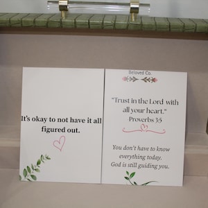 May include: Open green textured box with a clear handle and gold accents. Inside, two white cards display inspirational quotes and floral accents. One card reads "It's okay to not have it all figured out." The other card says "Trust in the Lord with all your heart."