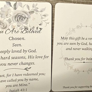 May include: Two rectangular white cards with rounded corners. The left card features a grey floral illustration and text: You Are Beloved, Chosen, Seen, Deeply loved by God, Even in hard seasons, His love for you never changes, Fear not, for I have redeemed you; I have called you by name, you are Mine. - Isaiah 43:1. The right card has a circular leaf border and text: May this gift be a reminder that you are seen by God, held with grace, and never walking alone. Thank you for being here. Thank you for supporting Beloved Co.