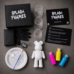 May include: A DIY paint kit featuring a white bear figurine. The kit includes a black box and instructions with the text "SPLASH FIGURES", paint bottles in pink, yellow, and blue, a paintbrush, and a plate. Also included are gloves, cups, and a keychain.