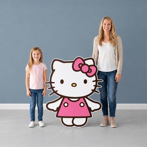 Puede incluir: Un recorte grande y plano del personaje Hello Kitty con cara blanca, un lazo rosa brillante y un vestido rosa con dos detalles circulares blancos. El personaje tiene contornos negros, bigotes negros, una nariz amarilla y dos ojos ovalados.
