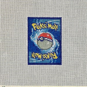May include: A needlepoint canvas featuring the back design of a Pokémon trading card. The rectangular image displays a blue background with a central red and white Poké Ball graphic, surrounded by a swirling white pattern and yellow Pokémon text.
