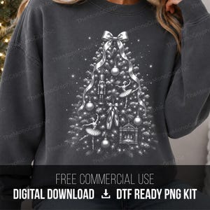 May include: A charcoal gray crewneck sweatshirt featuring a white graphic of a Christmas tree decorated with ballet-themed ornaments including a nutcracker, ballerinas, pointe shoes, and a stage, topped with a large white ribbon bow.