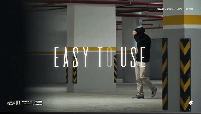 以下が含まれることがあります： 駐車場を背景に「EASY TO USE」の文字が書かれた画像。黒いパーカーとカーキ色のズボンを履いた人物がカメラから離れて歩いています。コンクリートの柱と黄黒の安全標識があり、薄暗いシーンです。