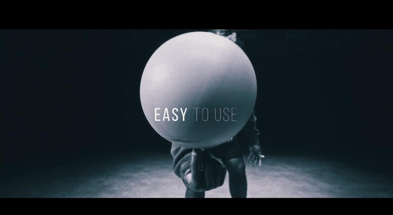 May include: A grayscale image features a large, spherical object held by a person. The text "EASY TO USE" is displayed on the sphere. The background is dark, creating a contrast with the bright sphere.