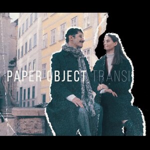 May include: A vintage-style image with the text "PAPER OBJECT TRANSITION". A man and a woman are seated outdoors, with a city backdrop. The man wears a dark coat and scarf, the woman a dark coat. The image has a distressed, aged effect.