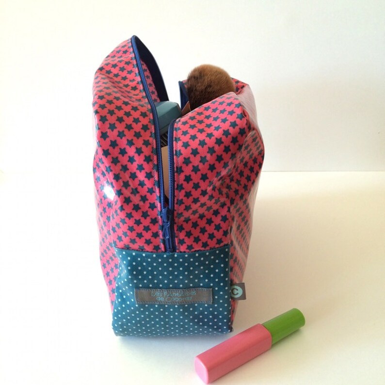 May include: Red and blue zippered toiletry bag with a star pattern and a blue and white polka dot bottom. The bag has a label that reads "Les Petites  de Cocotay".