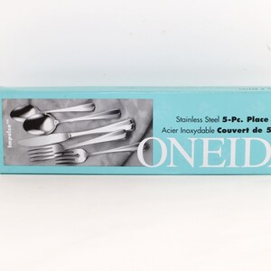 May include: A rectangular light blue box for a Oneida stainless steel 5-piece place setting. The box features a graphic of a spoon, knife, and fork, with the text "Stainless Steel 5-Pc. Place Setting" and "ONEIDA" printed in black and white.