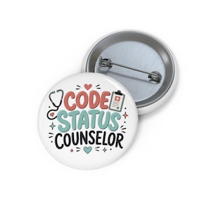 May include: A round pin-back button featuring a white background with the text CODE STATUS COUNSELOR in coral, teal, and black. The design includes a black stethoscope, a medical clipboard icon, and small coral hearts and star accents.