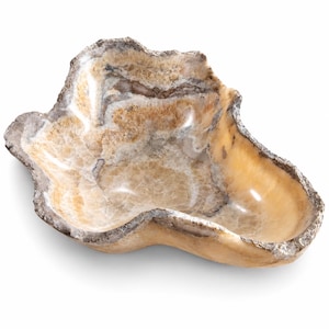 May include: A polished stone bowl with an irregular, organic shape and a rough, textured outer rim. The interior features a smooth, translucent surface with swirling patterns of cream, beige, tan, and dark brown mineral veining throughout.