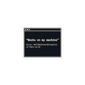 May include: A white sticker with a black screen graphic. The screen displays the text "Works on my machine" above an error message: "Error: NullReferenceException at Main.cs:42". The sticker has a white border.
