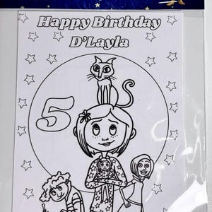 Op de afbeelding: Een Coraline verjaardagskleurplaat in een doorzichtige plastic hoes. De koptekst bevat de tekst Coraline Coloring sheets en een afbeelding van een personage. De pagina toont Happy Birthday D'Layla, een groot cijfer 5, sterren en figuren.