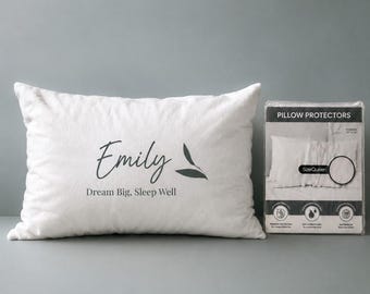 Könnte beinhalten: Ein weißes rechteckiges Kissen mit dem Namen Emily in schwarzer Schreibschrift, einer kleinen Blattgrafik und dem Text Dream Big, Sleep Well. Daneben befindet sich eine durchsichtige Kunststoffverpackung mit der Aufschrift Pillow Protectors, Größe Queen, 51 cm mal 76 cm.