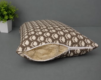 Könnte beinhalten: Ein rechteckiges Dekokissen mit einem braunen Stoffbezug und einem sich wiederholenden weißen Blumenmuster. Das Kissen hat einen weißen Reißverschluss an einer Seite, der teilweise geöffnet ist und eine flauschige, helle Füllwatte zeigt.
