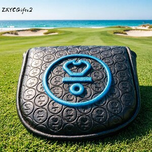 Puede incluir: Funda negra para la cabeza del palo de golf con un emblema bordado en azul. La funda tiene un patrón texturizado y está colocada en un campo de golf verde con vista al océano. El texto "ZXYCGifts2" está en la esquina superior izquierda.