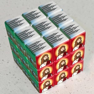 May include: A cube puzzle with images of a church building and a figure with a beard and halo. The church images are on a green and blue background, while the figure is on a red background.