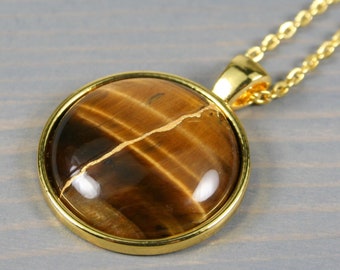 Kintsugi repaired tiger eye pendant in a gold plated bezel setting on a chain necklace