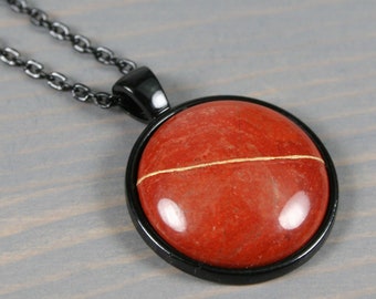 Kintsugi repaired red jasper pendant in a black bezel setting on a black cable chain necklace