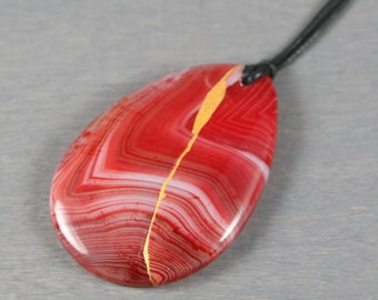 Kintsugi repaired red banded agate teardrop pendant on an adjustable length black cotton cord necklace