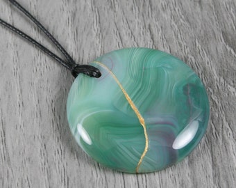 Kintsugi repaired green banded agate pendant on an adjustable length black cotton cord necklace