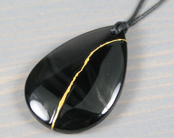 Kintsugi repaired black agate teardrop pendant on an adjustable black cotton cord necklace
