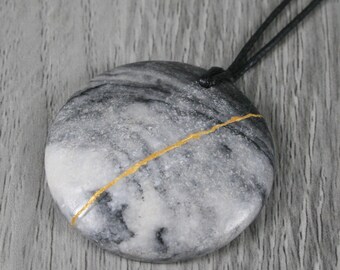 Kintsugi repaired black and grey marble pendant on an adjustable length black cotton cord necklace