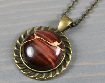 Kintsugi repaired red tiger eye pendant in an antiqued brass setting on chain