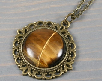 Kintsugi repaired tiger eye pendant with an antiqued brass setting on cable chain