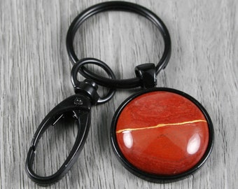 Kintsugi repaired red jasper key chain in a black bezel setting with swivel lobster claw