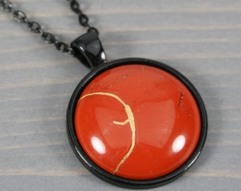 Kintsugi repaired red jasper pendant in a black bezel setting on black chain