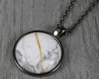 Kintsugi repaired white howlite pendant in a gunmetal plated bezel setting on a chain necklace