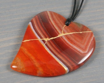Kintsugi repaired red-orange banded agate broken heart pendant on black cotton cord