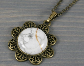 Kintsugi repaired white howlite pendant with an antiqued brass flower setting on cable chain