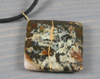 Kintsugi repaired frement jasper pendant on a thick black cotton cord necklace