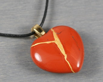 Kintsugi repaired red jasper broken heart pendant on a black cotton cord necklace