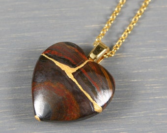 Broken heart pendant in red tiger iron with kintsugi repair on a cable chain necklace