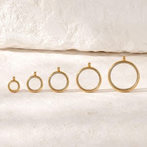 Può includere: Cinque medaglioni circolari in metallo color oro disposti in fila dal più piccolo al più grande. Ogni medaglione presenta una sottile cornice dorata, un centro trasparente e un piccolo anello dorato sulla parte superiore per l'aggancio.