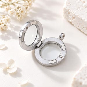 Peut inclure: Un médaillon circulaire en métal argenté avec une conception à charnière et des panneaux en verre transparent. Le médaillon présente de petites fermetures magnétiques le long du bord intérieur et une petite boucle en métal sur le dessus.