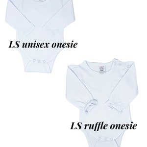 May include: Two white long-sleeve onesies for babies. The onesie on the left has a plain long sleeve, while the onesie on the right has a ruffle on each sleeve. Both onesies have a snap closure at the crotch.