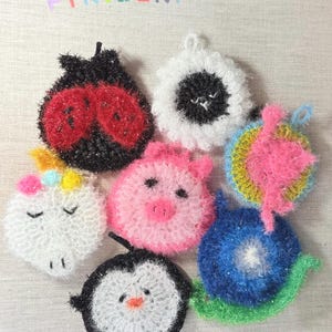 May include: Seven colorful crocheted dishcloths with animal designs. The designs include a ladybug, a pig, a unicorn, a penguin, a snail, a cat, and a flower.