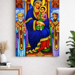 Puede incluir: Un icono religioso vibrante con una figura central con una túnica azul que sostiene a un niño, ambos con halos. Dos figuras los flanquean, y dos ángeles están en la parte superior. La obra de arte es rica en color, con detalles dorados e intrincados, sobre lienzo.
