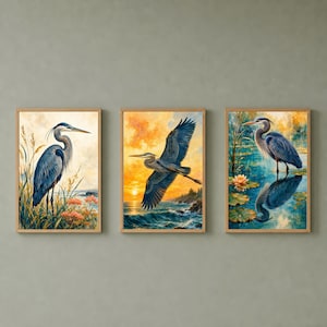 以下が含まれることがあります： アオサギを描いた3枚の額入りウォールアートプリントのセット。1枚目は背の高い草の中に立つサギ、2枚目は夕暮れの海の上を飛ぶサギ、3枚目は水辺に立ち、水面に姿が映り込んでいるサギが描かれています。