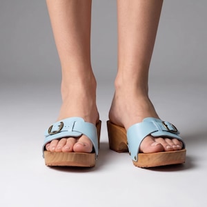 Tamancos femininos azuis, modelo slip-on com sola de madeira, ideais para o conforto no verão.